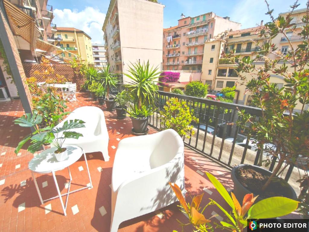 a balcony with white chairs and plants and buildings at Foce 24 - City Garden 2 - in Imperia