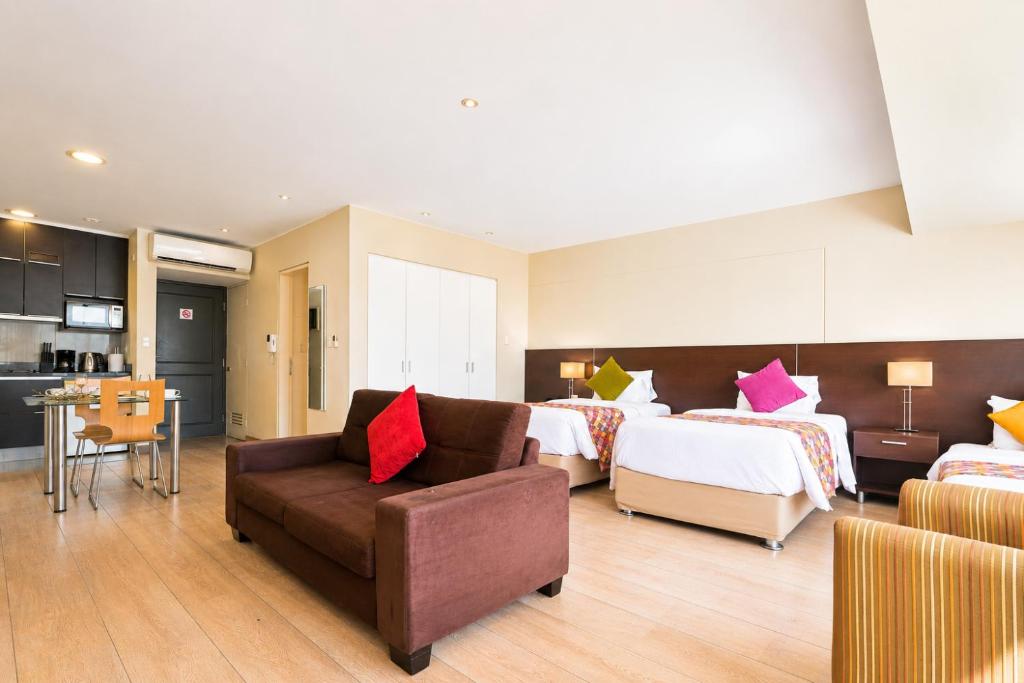 a hotel room with two beds and a couch at Diez Canseco by 2W Aparments Service in Lima