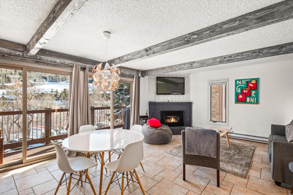 a dining room with a table and chairs and a fireplace at 29C by SkyRun Aspen in Snowmass Village