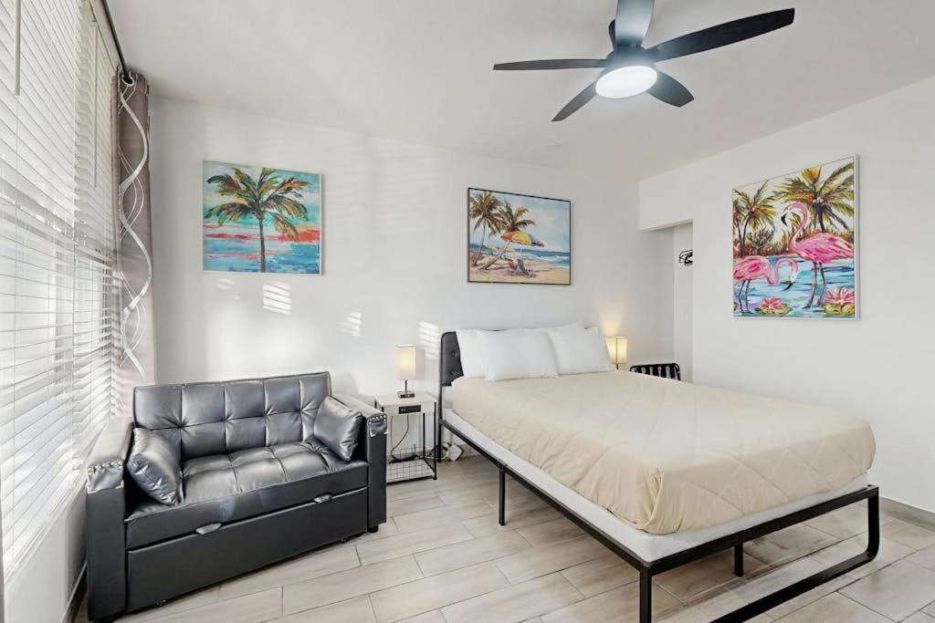 a bedroom with a bed and a couch and a ceiling fan at Sunshine, Beach & Smiles on Ocean Drive in Miami Beach