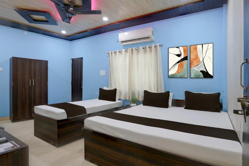 two beds in a room with blue walls at Hotel O by OYO Shree Paying Guest House in Varanasi