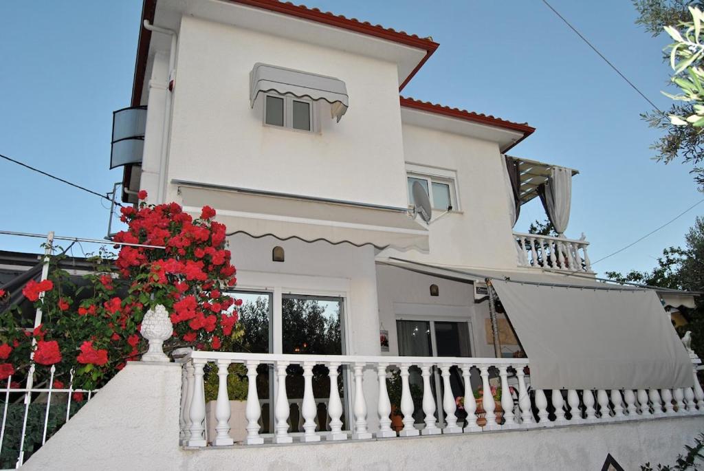 ein weißes Haus mit Balkon und roten Blumen in der Unterkunft Amalia's Maisonette in Marathos