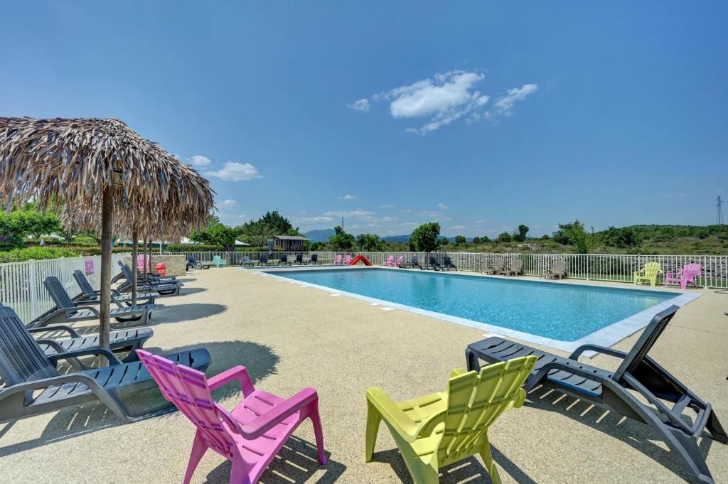 a group of chairs sitting around a swimming pool at Camping Olé camp in Balazuc