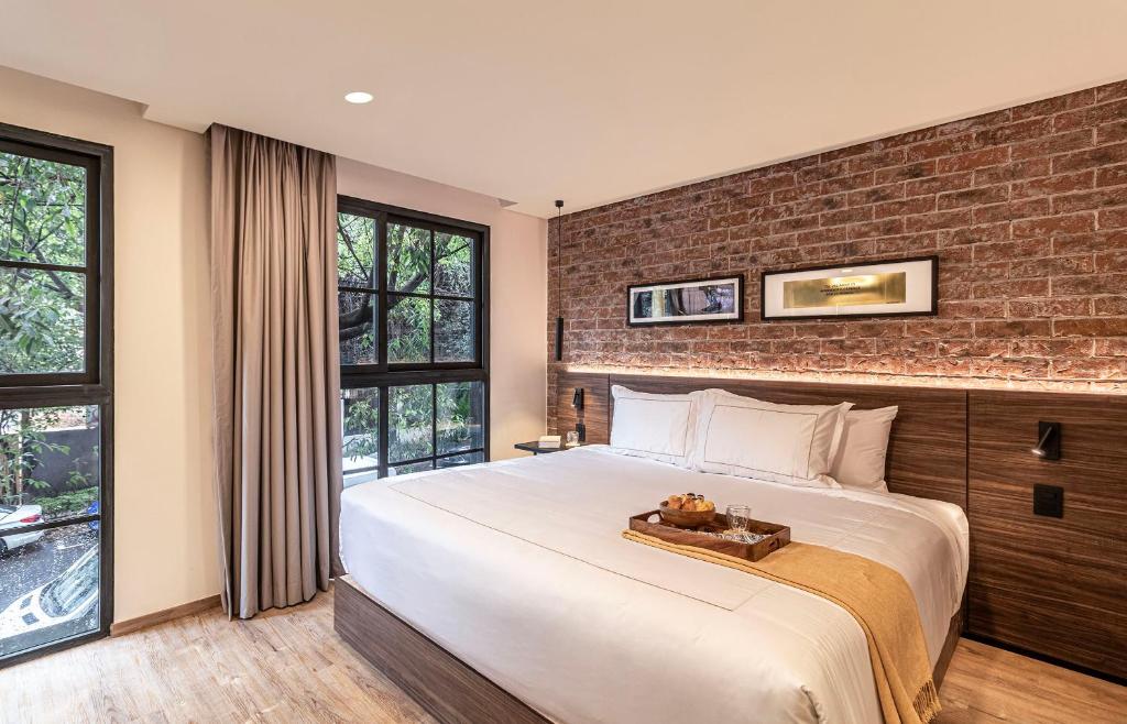 a bedroom with a large bed with a brick wall at Kukun Edition El Angel in Mexico City