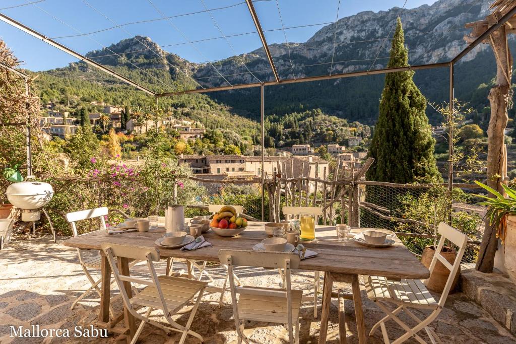 a table on a patio with a view of a city at C'an Llum in Deia