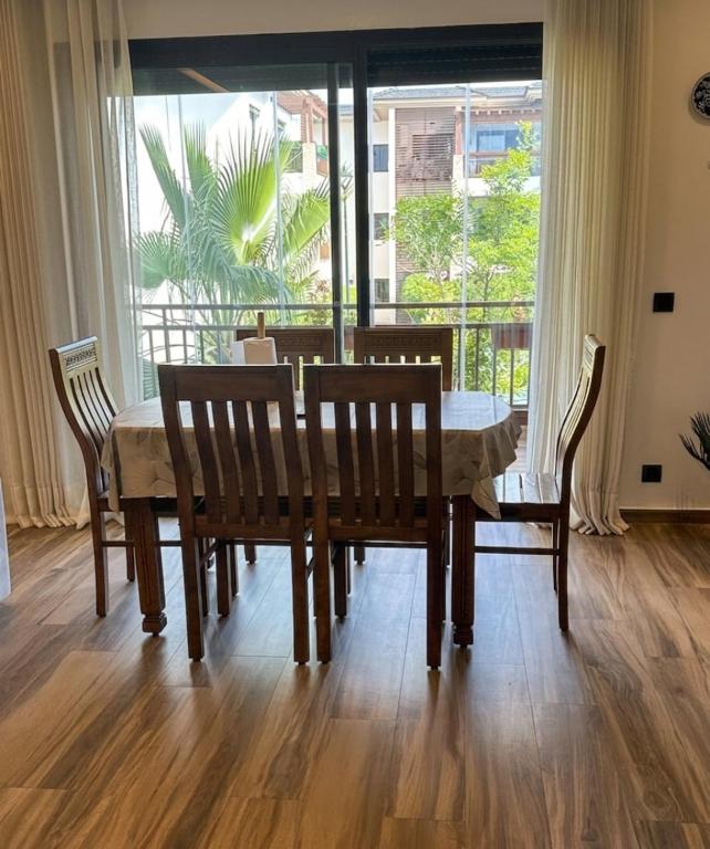 a dining room with a table and chairs and a window at Joli appartement à Tamaris in Dar Bouazza