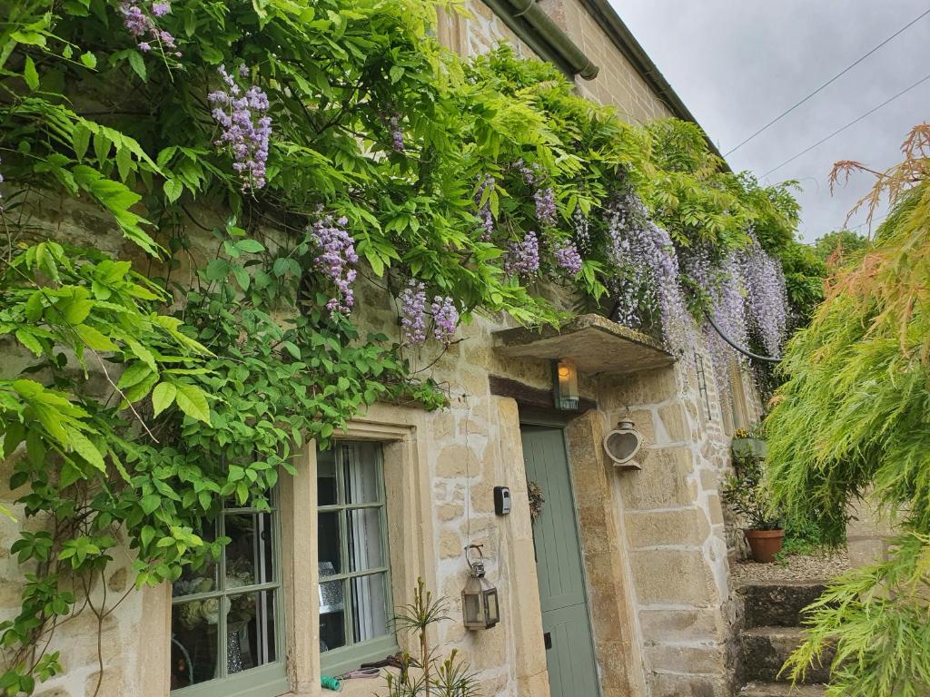 a building with purple flowers on the side of it at Lamb Cottage Bed and Breakfast in Box