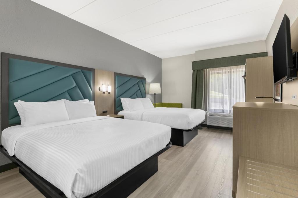 a hotel room with two beds and a flat screen tv at Best Western Eagles Inn in Morehead