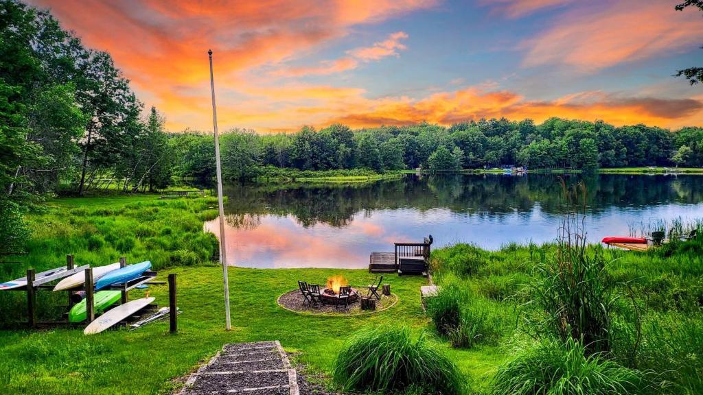 a fire pit next to a lake at sunset at Chalet All Day by AvantStay in Arrowhead Lake