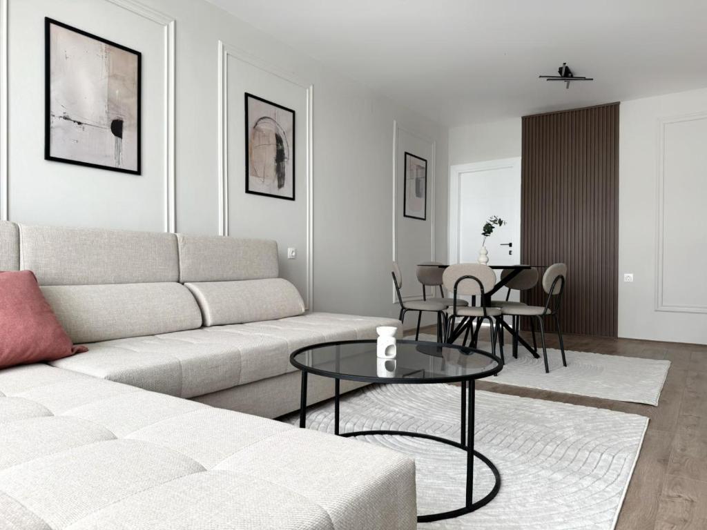 a living room with a white couch and a table at Zafiro Apartment, City Center in Kavadarci