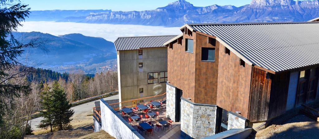 un edificio con tavoli e sedie su un balcone con vista sulle montagne di Village Vacances Les Ramayes a Prapoutel