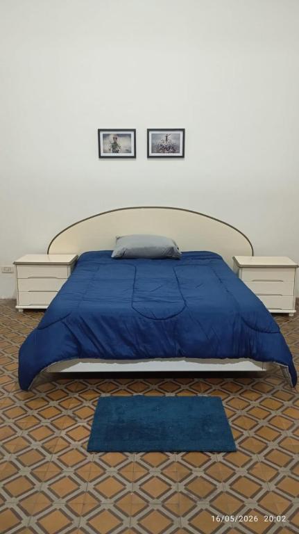 a bedroom with a large bed with a blue blanket at Hospedaje "Doña Tomasa" -A 15 minutos del aeropuerto -Parking in Ezeiza