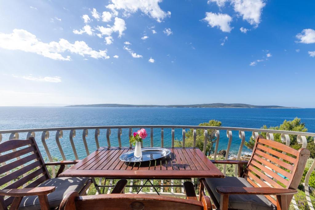 a wooden table with a vase of flowers on a balcony at Apartment Zavala 553d in Jelsa