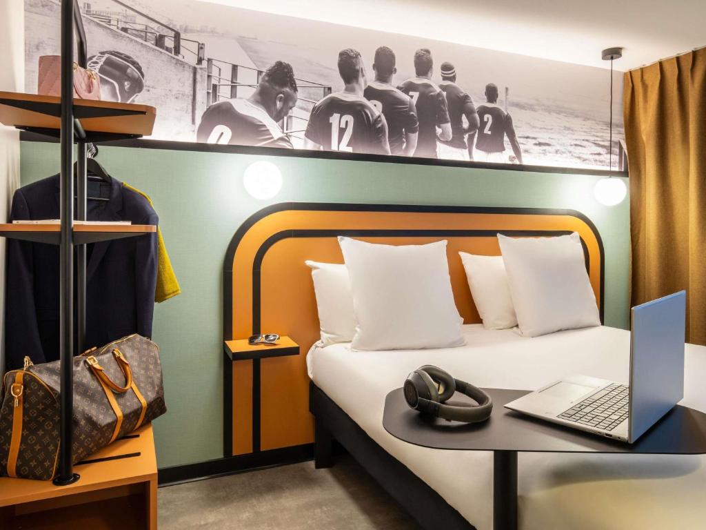 a bedroom with a bed with a laptop on a table at ibis Styles Colombes Paris Ouest (Ouverture Octobre 2025) in Colombes