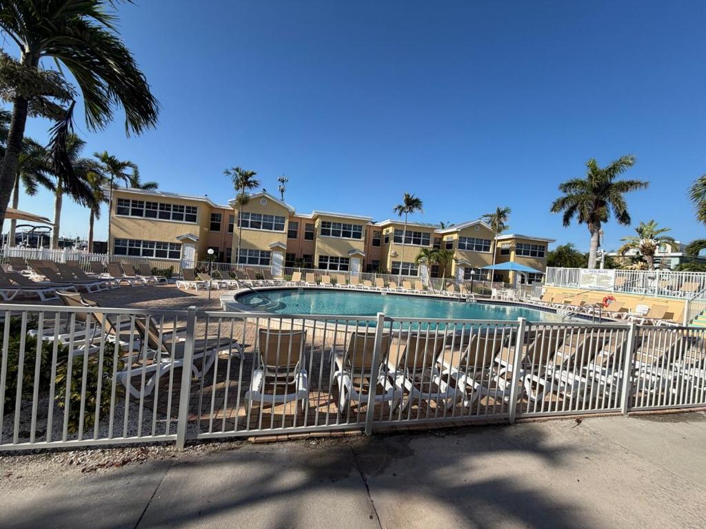 a pool with chairs and palm trees in a resort at Waves, Sun & Relaxation Retreat in Clearwater Beach