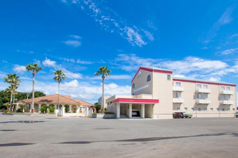 a building with palm trees in front of a parking lot at セントロ大隅ホテルオオサキ in Kanoya