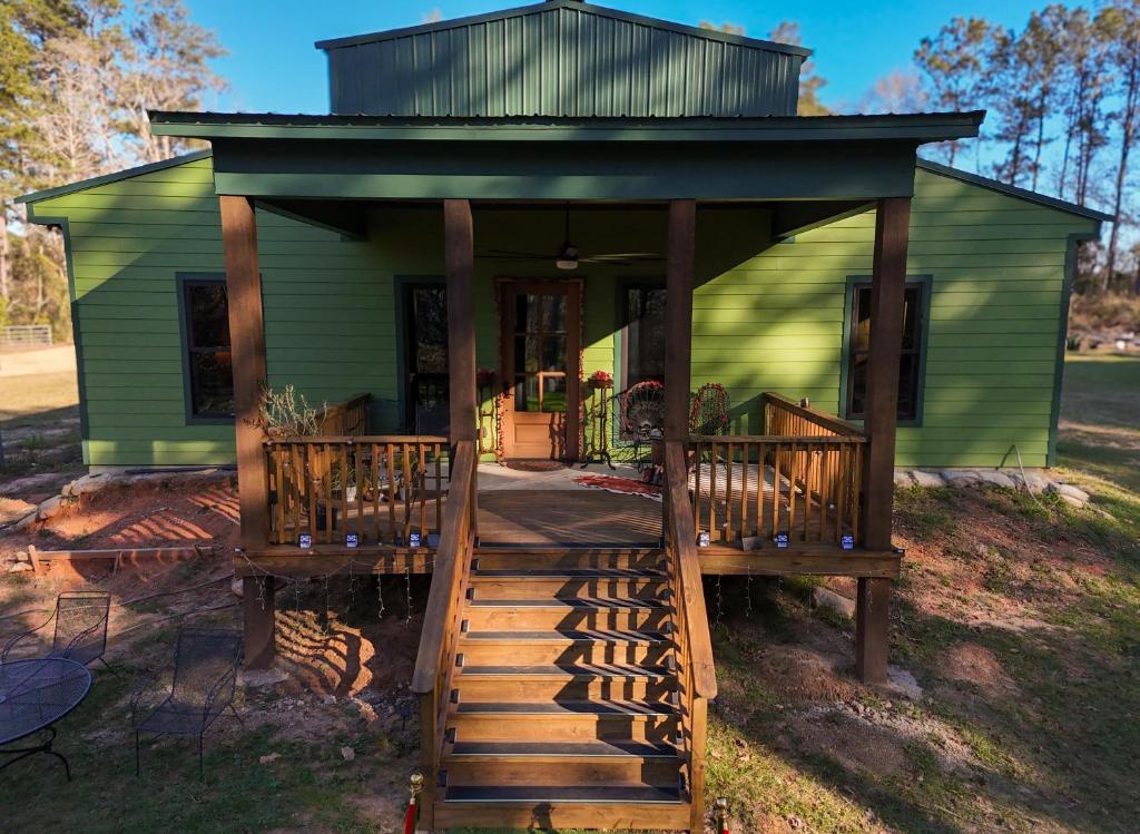 a green tiny house with a porch and stairs at Raka Ranch Barndominium in Folsom
