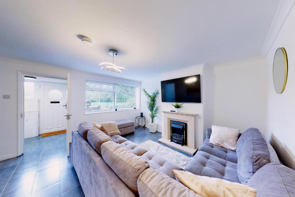 a living room with a large couch and a fireplace at 3 Bed Bedford House Parking WiFi Sleeps 5 in Bedford
