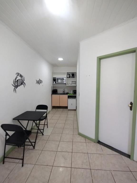 a room with a table and chairs and a kitchen at Casa Almendra in Búzios