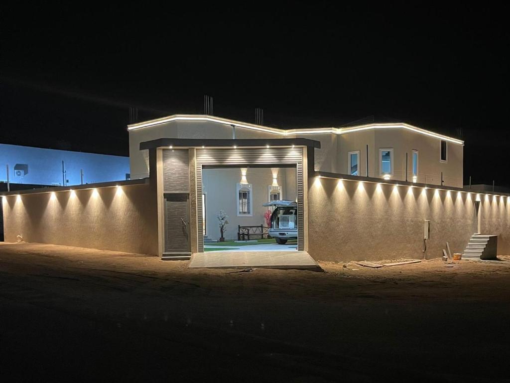 a white house with a wall with lights on it at شالية الفهد in As Sayl al Kabīr