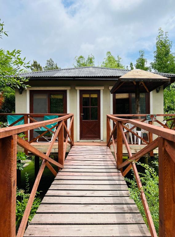 a wooden bridge leading to a house with a door at Victoria Cabañas in Tigre