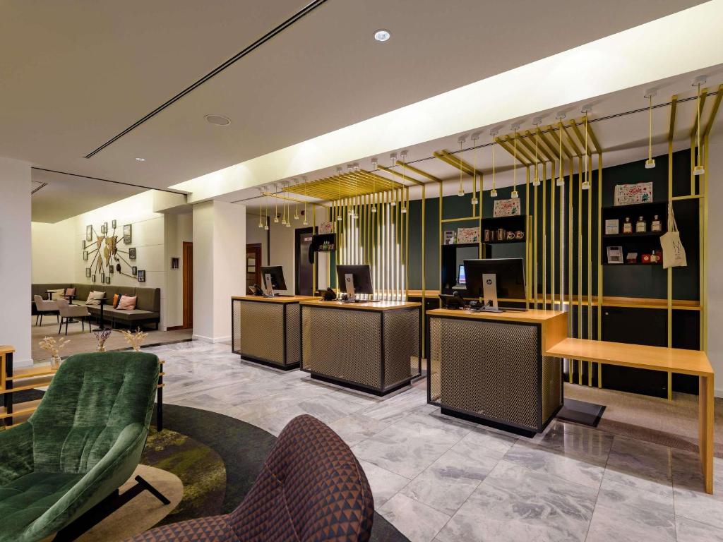 a lobby with a waiting area with chairs and tables at Hotel Mondial am Dom Cologne MGallery in Cologne