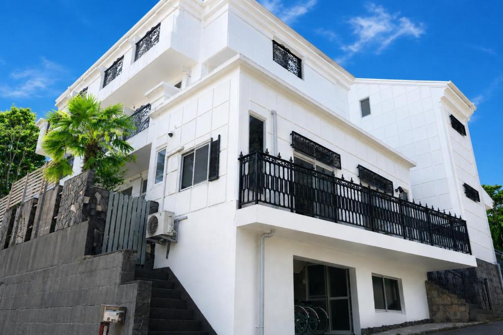 a white house with a balcony and a palm tree at 全室オーシャンビューの宿 ルーチェ須崎 in Shimoda