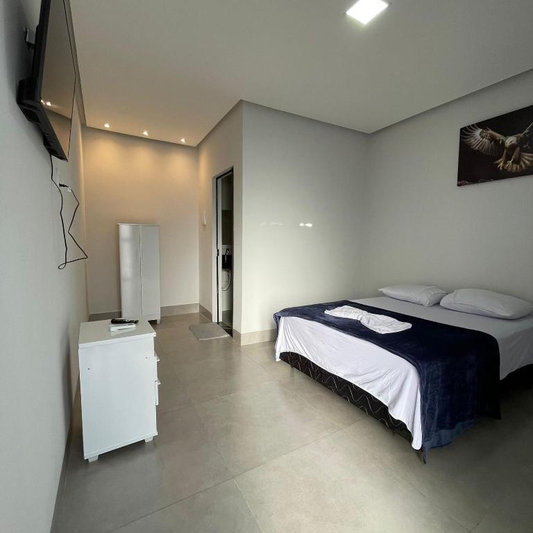 a bedroom with a bed and a television in it at Hotel Iluminar in Goianésia