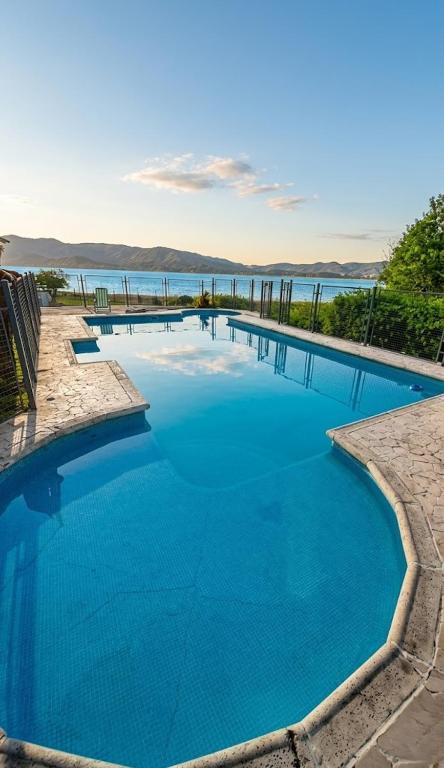 a large swimming pool with a view of the water at Cabañas Lago Azul in Villa Santa Cruz del Lago