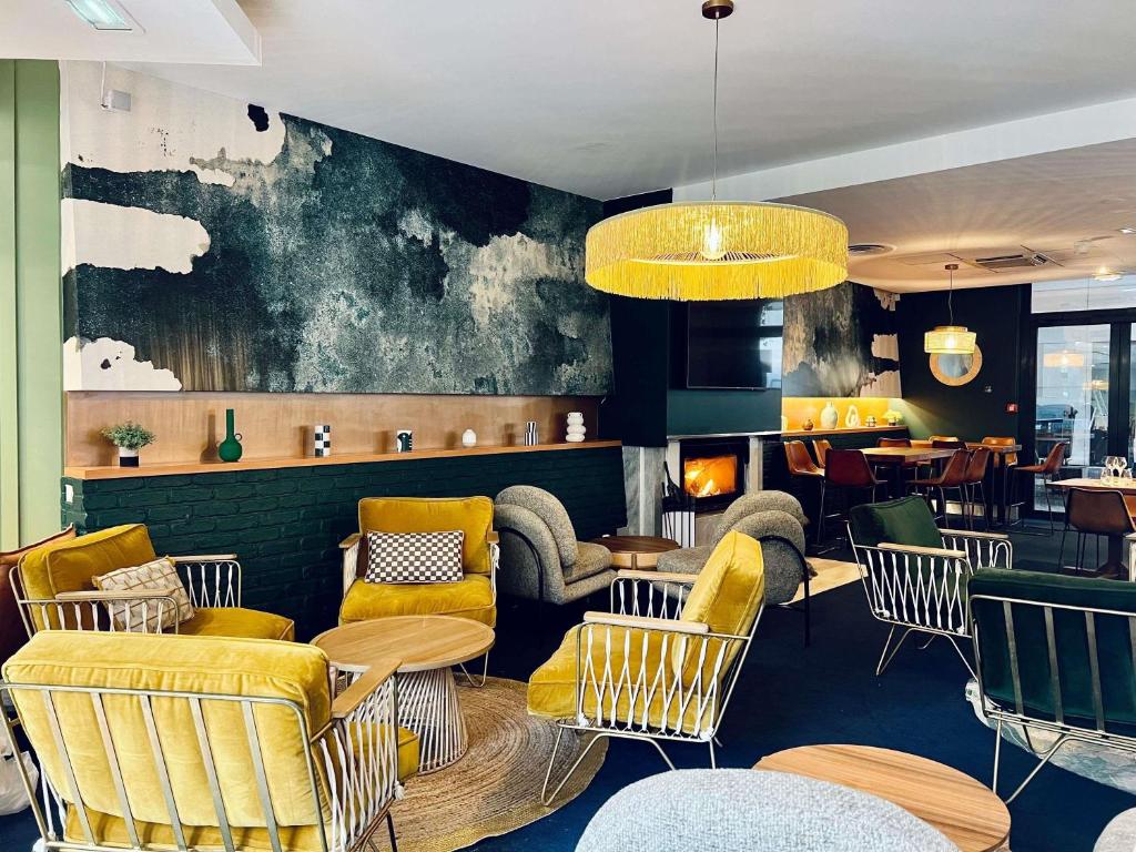 a restaurant with yellow chairs and tables and a fireplace at Novotel Paris Pont De Sevres in Sèvres