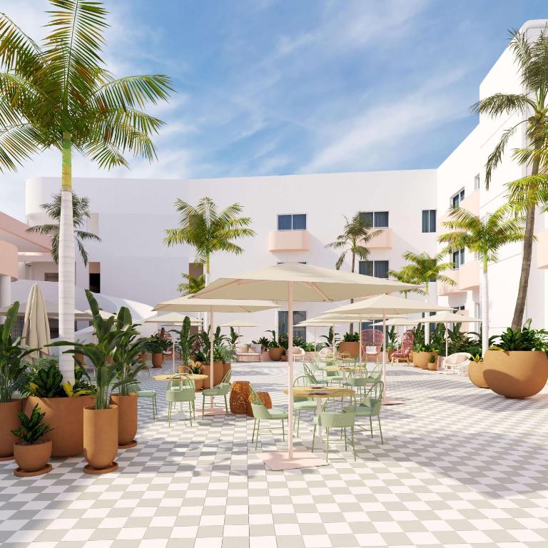 a courtyard with tables and chairs and palm trees at Perla La Paz, Tapestry Collection By Hilton in La Paz