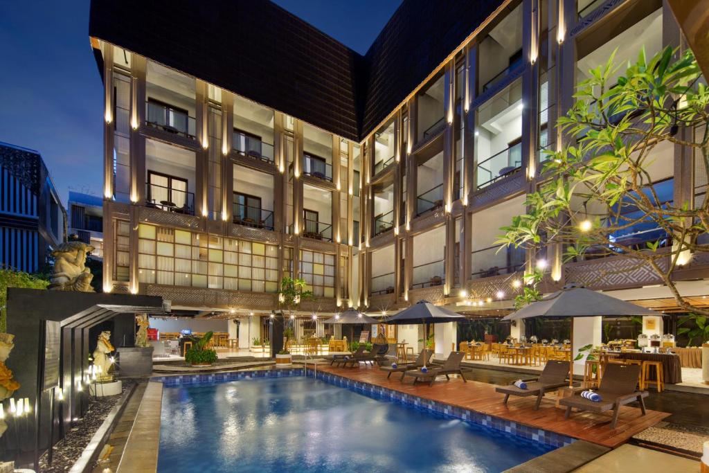 a hotel with a swimming pool in front of a building at Nadi Hotel Legian in Legian
