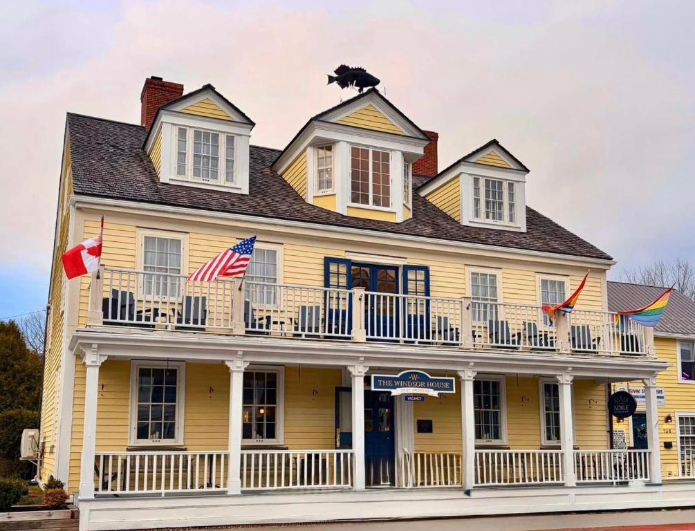 a yellow house with a balcony and a dog on the roof at Windsor House Inn in Saint Andrews