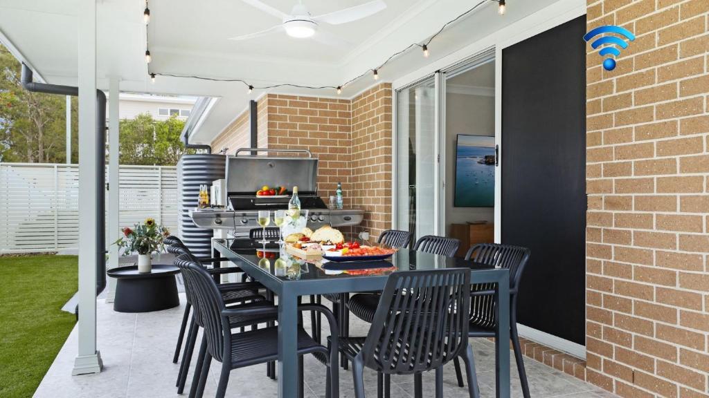 a patio with a table with chairs and a grill at Coastal Drift in Callala Bay