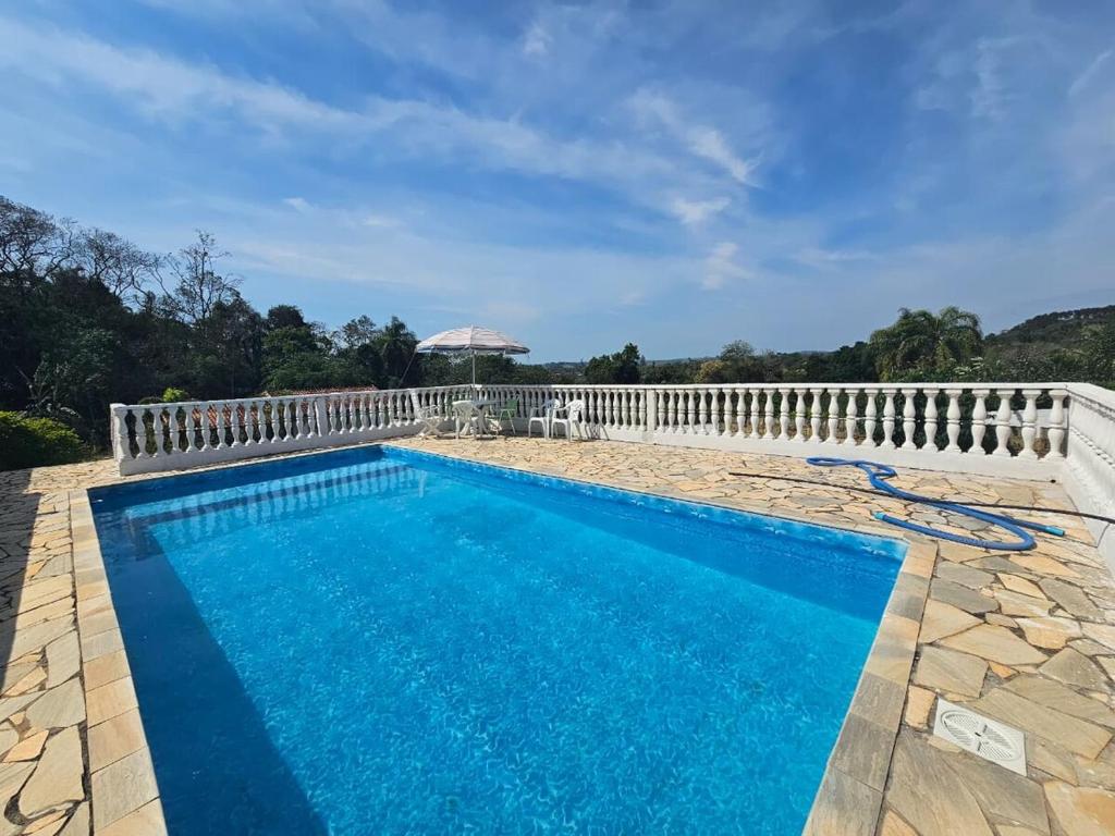 a swimming pool with a white fence and blue water at Rancho da Benção in São Roque