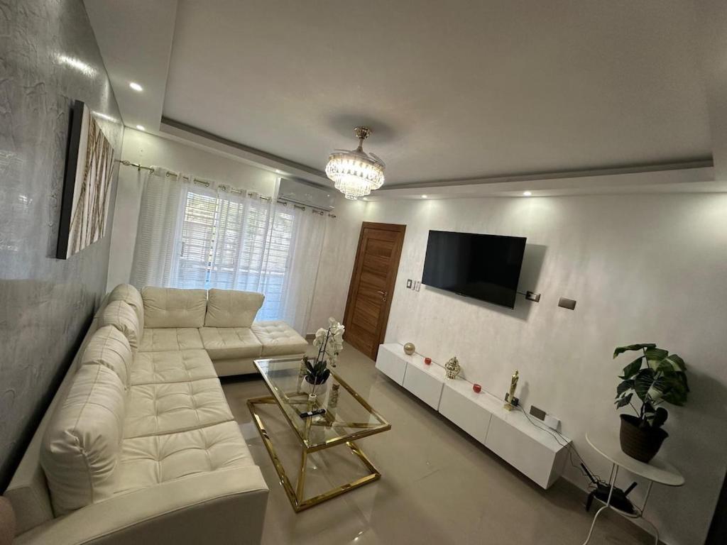 a living room with a white couch and a tv at Elegant and comfortable and exclusive first level in Santo Domingo