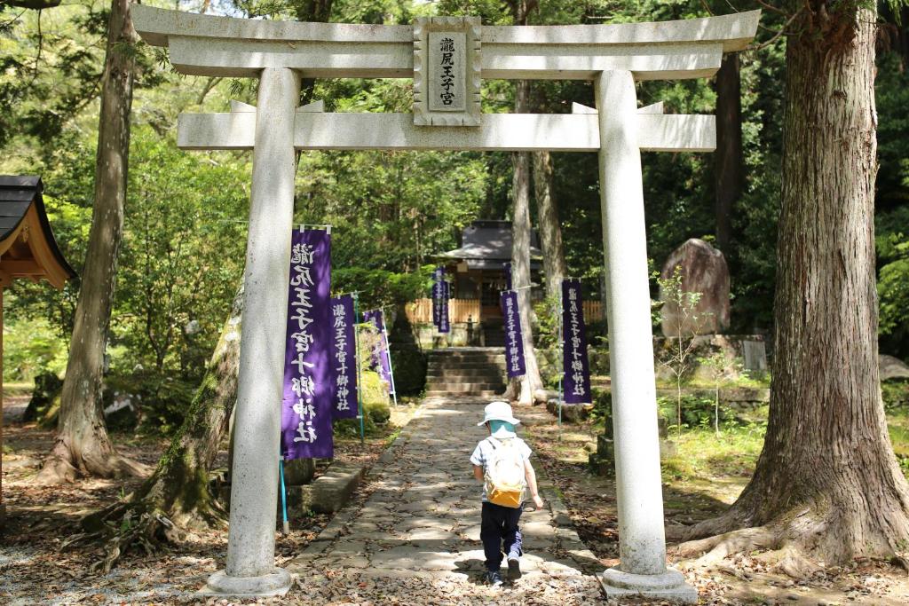 a little child walking through a torii gate at SEN RETREAT TAKIJIRI - Kumano Kodo Gateway in Tanabe