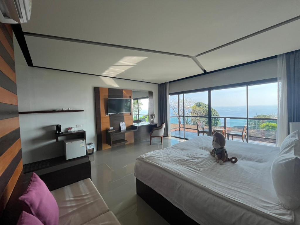 a bedroom with a large bed and a large window at Secret Cliff Resort & Restaurant - SHA Plus in Karon Beach