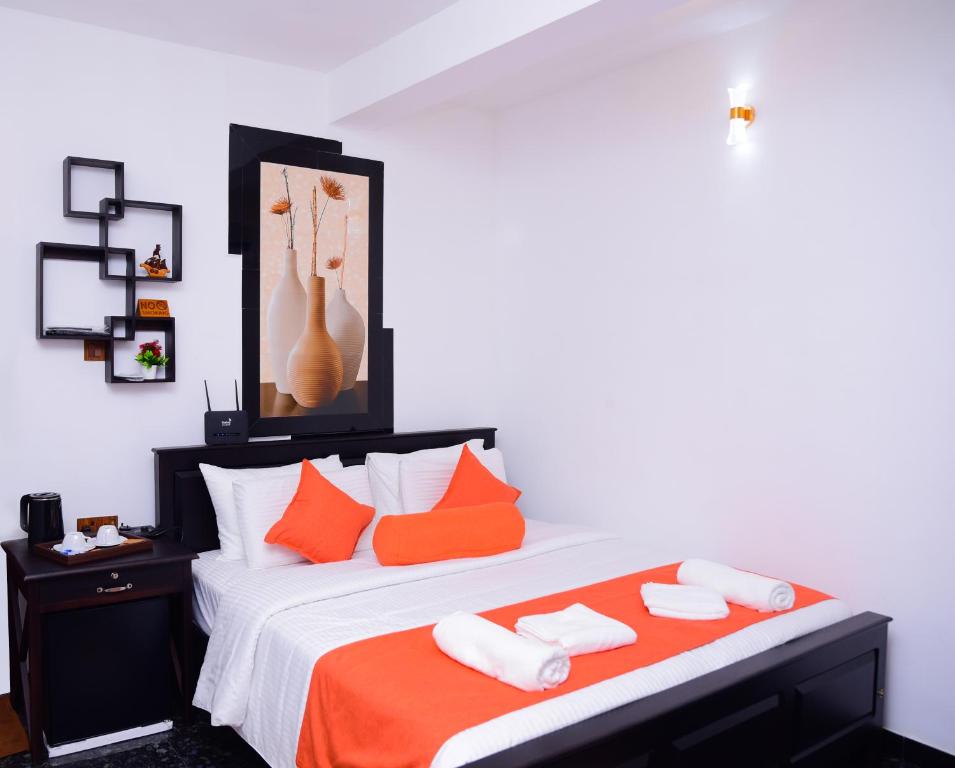 a bedroom with a large bed with orange and white pillows at Thenulya Resort in Ella