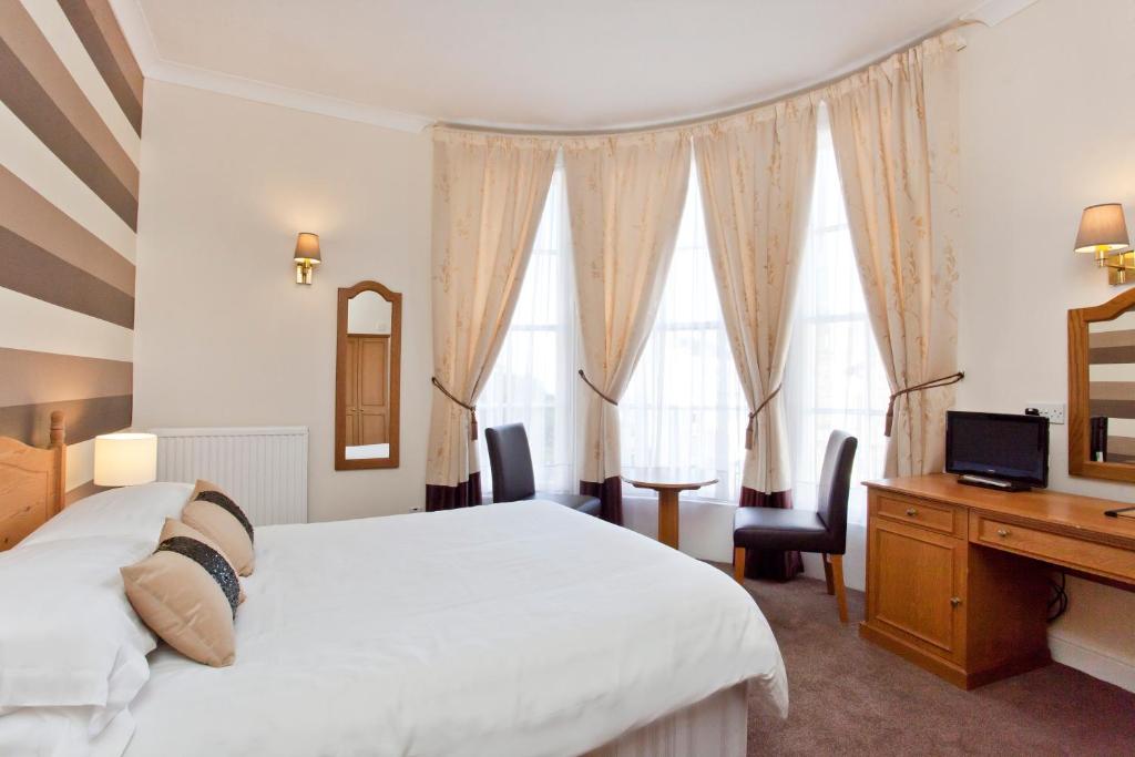um quarto com uma cama, uma secretária e janelas em The Dickens Bar & Inn em Scarborough