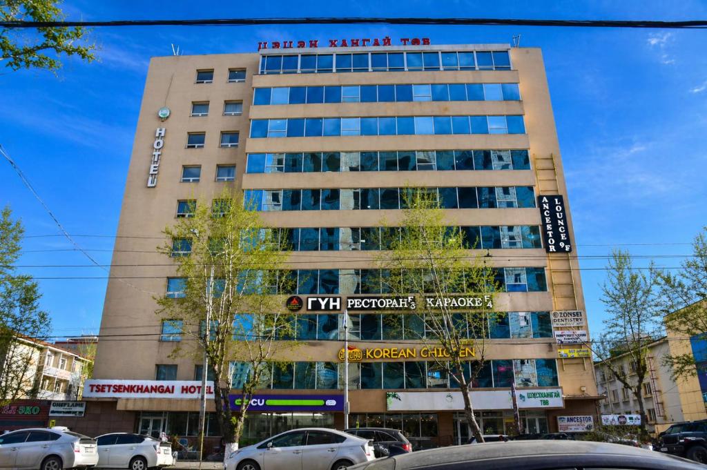 a tall building with cars parked in front of it at Tsetsenkhangai Hotel in Ulaanbaatar