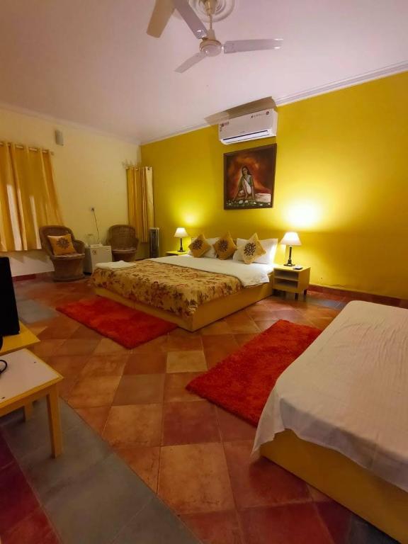 a bedroom with two beds and a yellow wall at The Nagri Resort in Pālampur