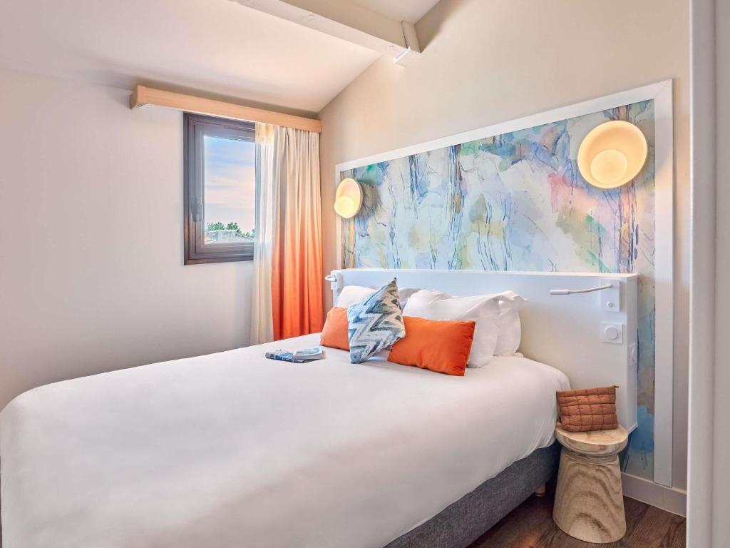 a bedroom with a large white bed with orange pillows at Aparthotel Adagio Aix-en-Provence Centre in Aix-en-Provence