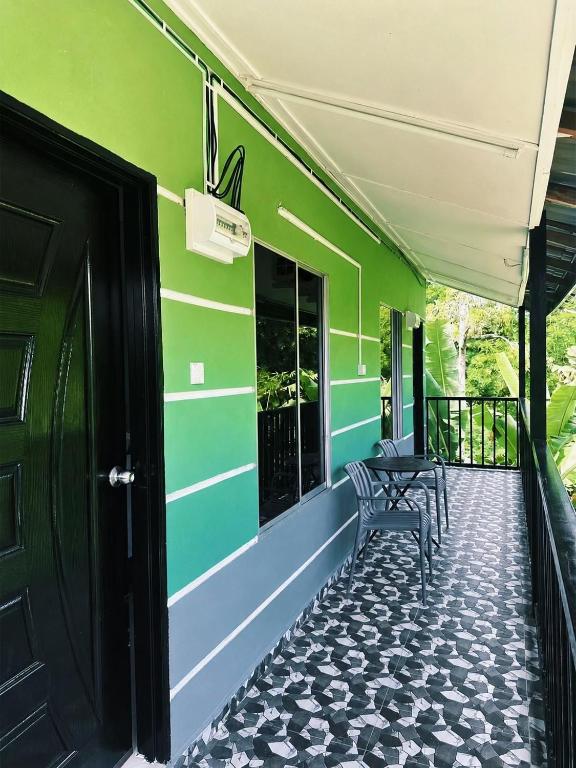 a green building with a porch with a bench at Rainbow River View in Jerantut