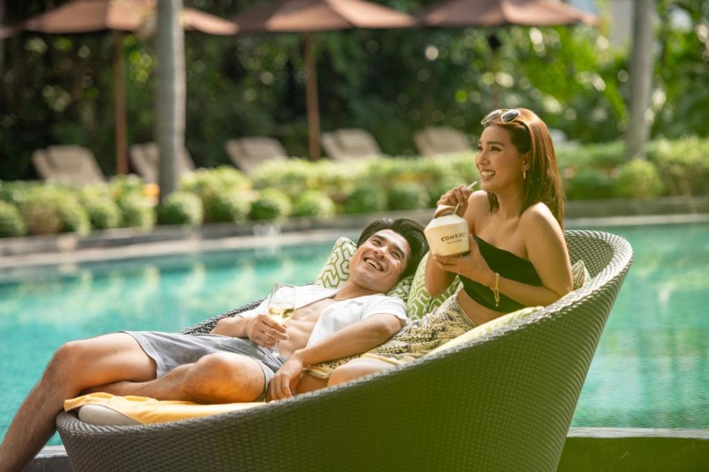 two people sitting in lawn chairs by a pool at Conrad Bangkok in Bangkok
