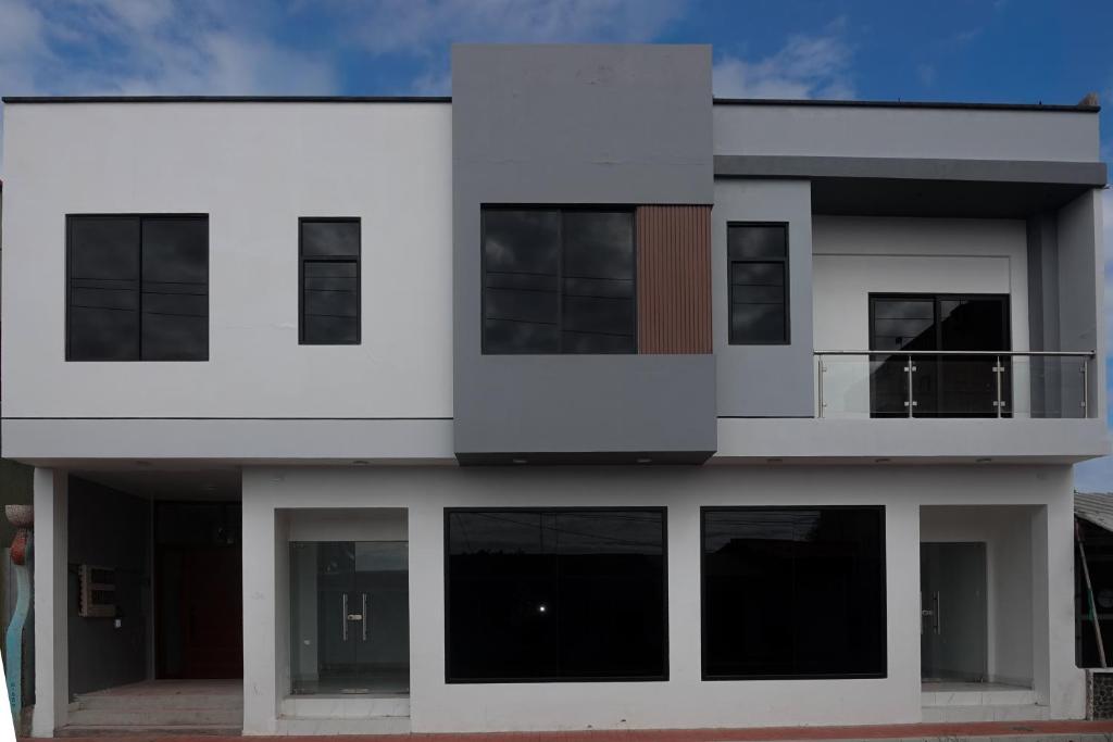 a white house with black windows and a balcony at San Cristóbal Surf House lll in Puerto Baquerizo Moreno