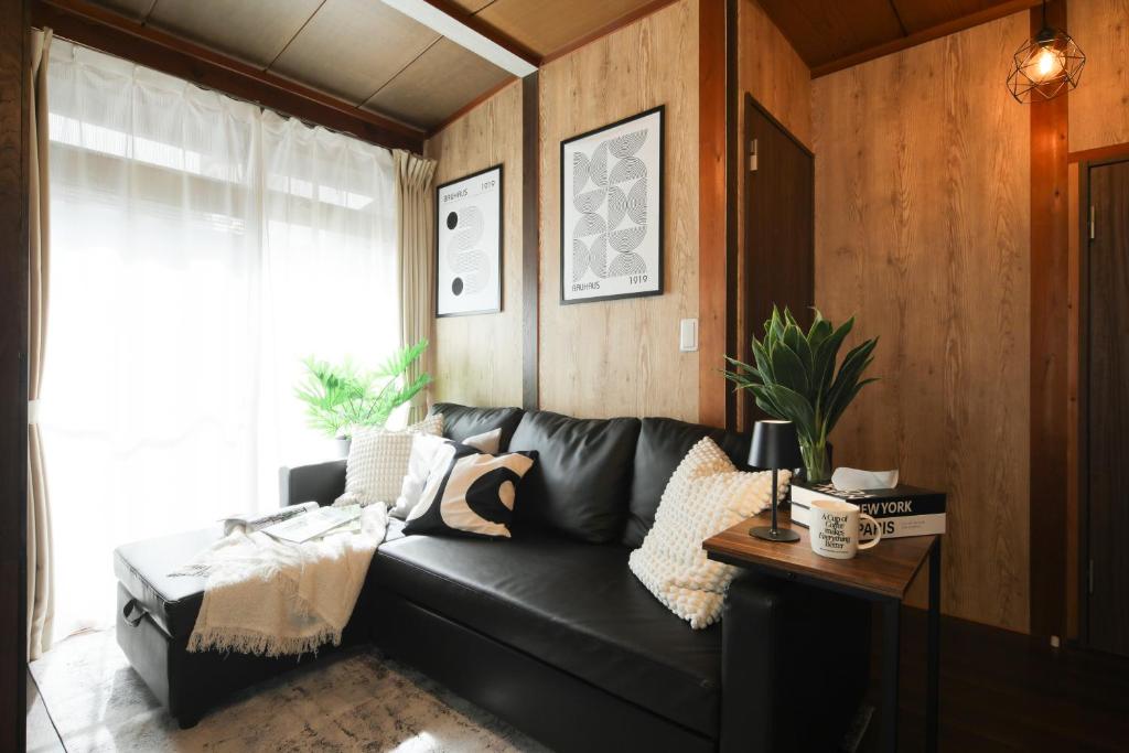 a black leather couch in a living room with a window at KiyosuBase2 in Kiyosu