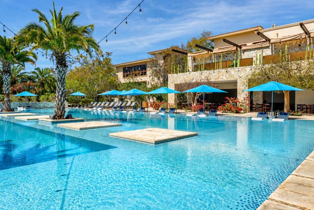 a pool at a hotel with blue umbrellas at Palmilla Dunes Luxury Residences in San José del Cabo