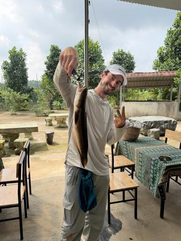 a man holding a fish on a fishing pole at Fish Farm Homestay in Yên Bái
