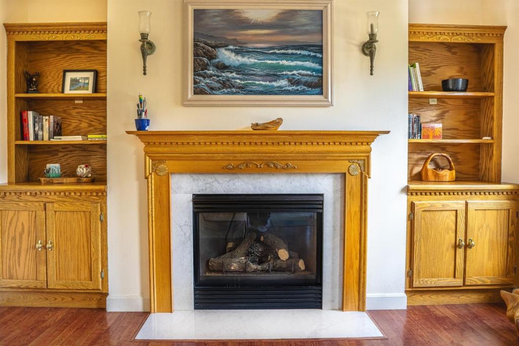 a fireplace in a living room with a painting on the wall at Spacious Seven Peaks Ridge Quiet Side Hot Tub, Pet Friendly, Fire Pit & Deck in Southwest Harbor
